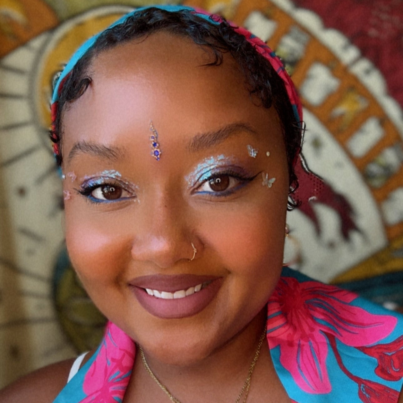 Woman with colorful headscarf and butterfly wings against a decorative background